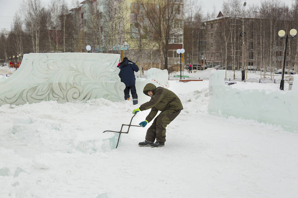 L'operaio tira il blocco di ghiaccio intorno al luogo di raccolta del campo di ghiaccio con pinze
 - Foto, immagini