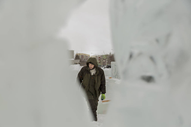 Retrato de un trabajador con una chaqueta verde con una capucha dedicada a organizar una ciudad de hielo
 - Foto, imagen