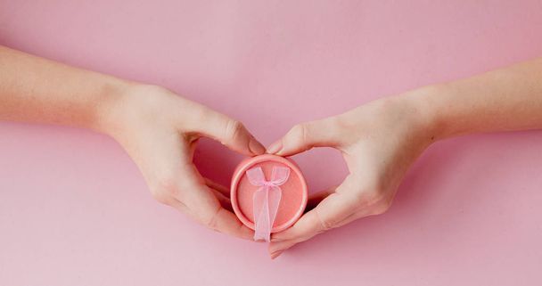 Pyöreä vaaleanpunainen lahjapakkaus naisten käsissä vaaleanpunaisella taustalla. Juhlallinen käsite Ystävänpäivä, äitienpäivä tai syntymäpäivä
. - Valokuva, kuva