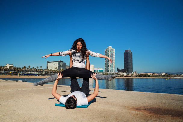 Hermosa pareja practicando acro yoga por la mañana
 - Foto, imagen