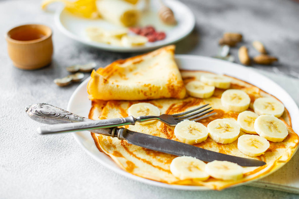 Cibo, dessert, pasticcini, pancake, torta. Belle frittelle saporite con banana e miele su uno sfondo concreto
 - Foto, immagini