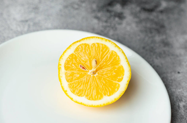 Citroen, fruit, citrus. Een frisse sappige citroen op een witte plaat op een concrete achtergrond - Foto, afbeelding