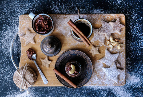 A beautiful Christmas still life of hot black coffee, homemade stars-shaped cookies, cinnamon sticks and flour and sugar sprinkles - Foto, immagini