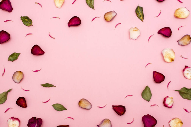 Pétalas de rosa marrom e folhas verdes em um fundo rosa. A vista de cima. Em branco para parabéns, cartões postais
. - Foto, Imagem