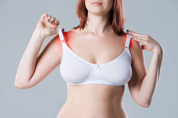 Woman with irritated skin under bra, irritation on the body from underwear on gray background, painful area highlighted in red - Foto, afbeelding