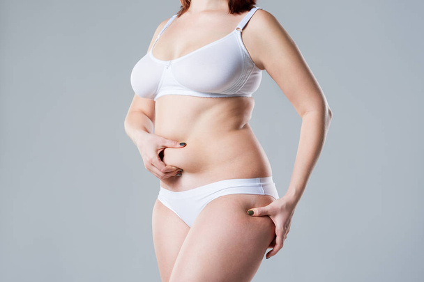 Woman with fat abdomen, overweight female body on gray background, studio shot - Foto, imagen