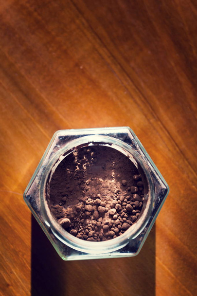 Cocoa powder in glass jar lying on wooden brown table, flat lay view, healthy diet - 写真・画像