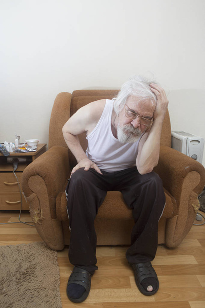 Un viejo enfermo solitario pobre hombre, que sufre de enfermedades oculares con cataratas y glaucoma, se sienta solo en una silla
. - Foto, Imagen