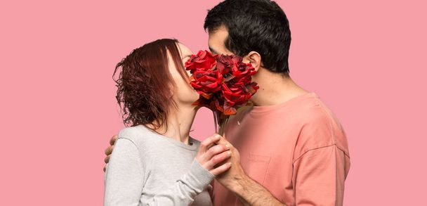 Couple in valentine day with flowers and kissing over isolated pink background - Foto, immagini