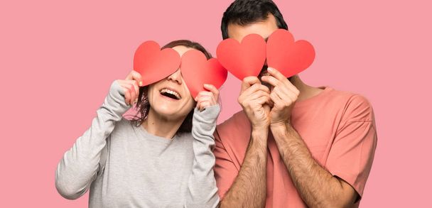 Couple in valentine day holding a heart symbol over isolated pink background - Foto, Bild