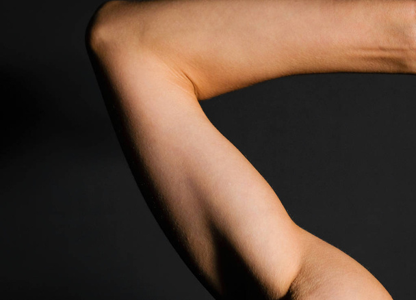 Fragment of a female arm on a black background - Foto, imagen