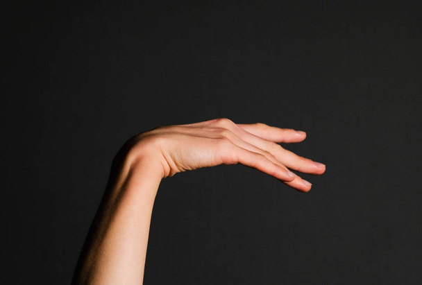 Elegant hand of a woman on a black background - Fotografie, Obrázek