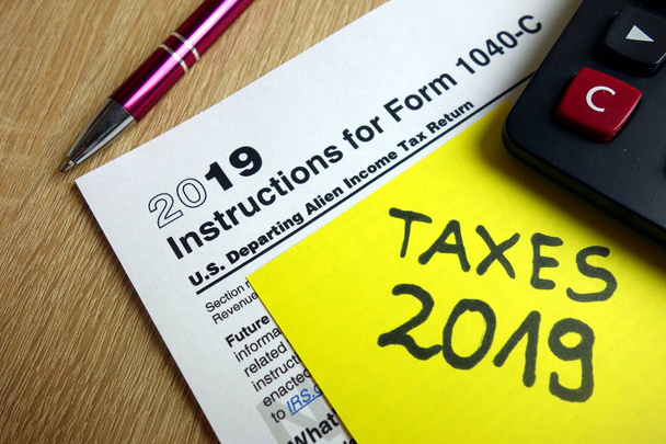 Ohjeet lomakkeeseen 1040-C, laskin ja kynä pöydällä, verokausi 2019
 - Valokuva, kuva