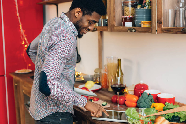Uomo nero ricetta di ricerca su tablet digitale in cucina
 - Foto, immagini