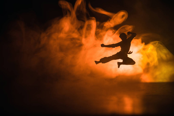 Каратэ спортсмены.Персонаж каратэ. Позирование украшения фигуры. Scramble or Man practicing karate on decorated foggy background with light
. - Фото, изображение