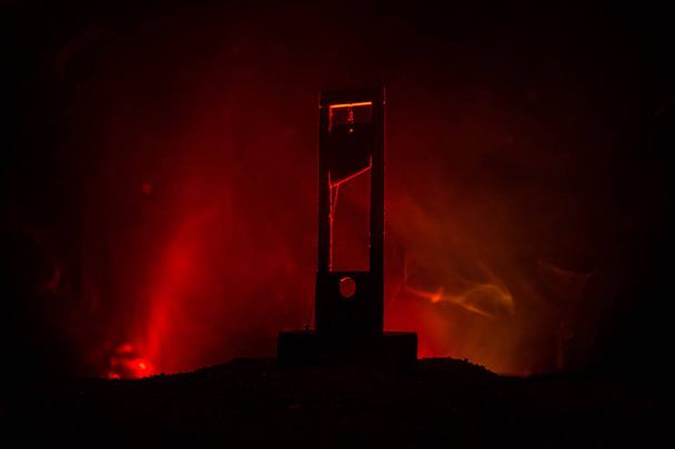 De weergave van de horror van de Guillotine. Close-up van een guillotine op een donkere, mistige achtergrond. Uitvoering concept - Foto, afbeelding