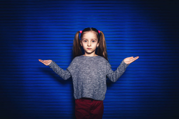 das kleine Mädchen zeigt Schuppen auf Händen auf blauem Hintergrund - Foto, Bild