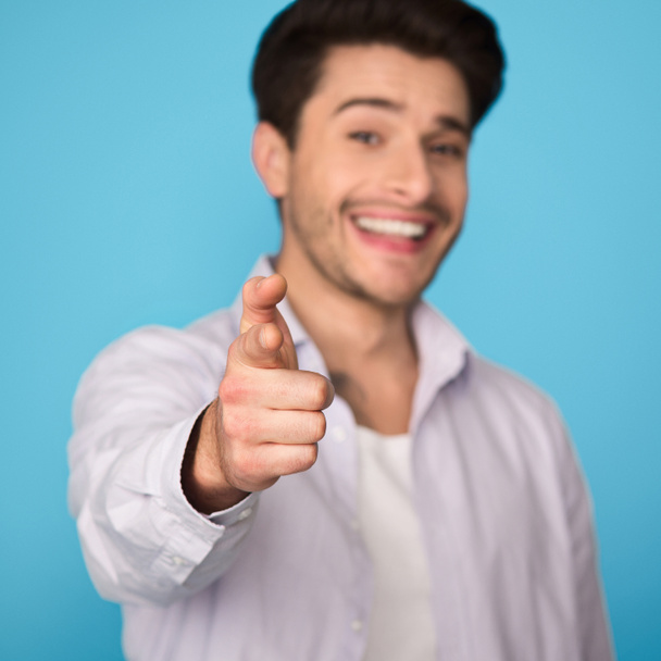 Man pointing finger at camera on blue background - Фото, изображение
