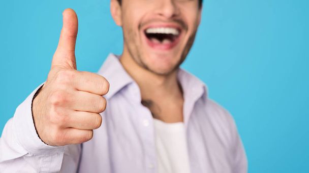 Задоволений чоловік показує великий палець вгору і посміхається
 - Фото, зображення