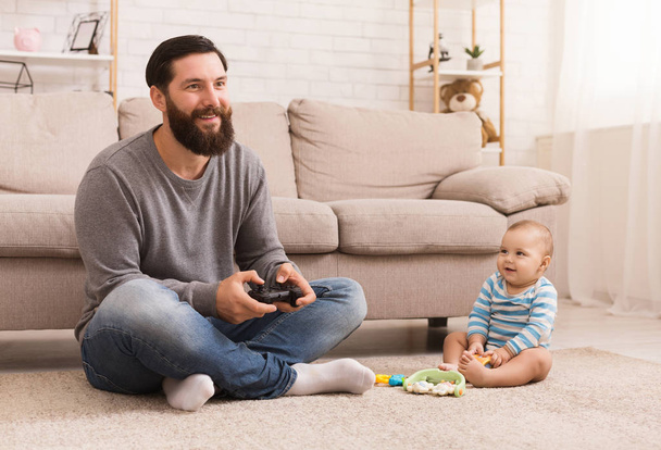 Adorable baby boy and his dad sitting playing video game - Photo, Image