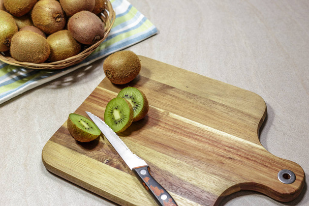Ripe whole kiwi fruits and slices on a cutting board with an old knife, prepares detox smoothie. - Foto, immagini
