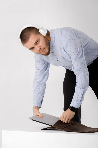businessman in headphones puts laptop in cover - Foto, Imagen