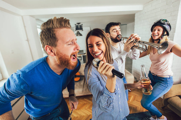 Grupa przyjaciół grająca w karaoke w domu. Koncepcja przyjaźni, rozrywki domowej i ludzi - Zdjęcie, obraz