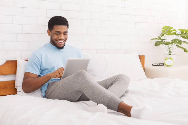 jovem millennial cara usando digital tablet na cama
 - Foto, Imagem
