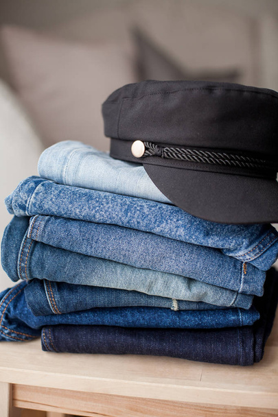 Jeans, schwarze Mütze, Jeansbaumwolle, blau. Stapel Jeans im Innenraum. Kleidung. Frühling. - Foto, Bild