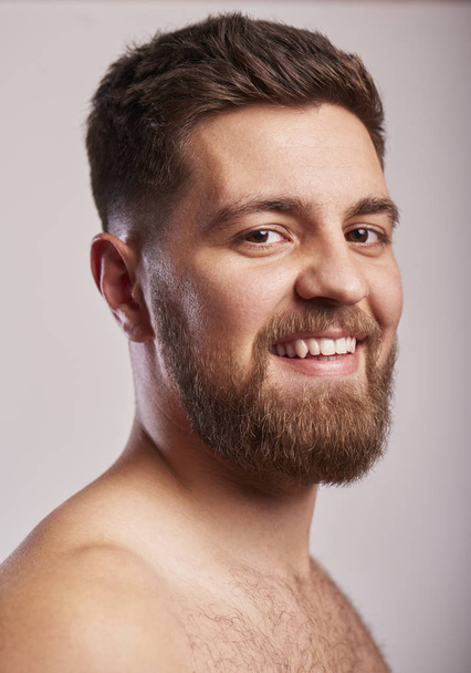 Привлекательный улыбающийся бородатый мужчина, стоящий на сером фоне
 - Фото, изображение