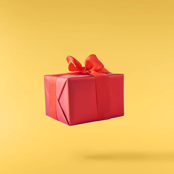 Valentines day concept.  Creative valentines day conception made by falling in air gift boxes and red hearts isolated on yellow background - Photo, Image