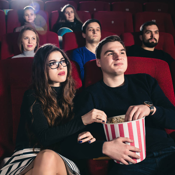 Una pareja enamorada coqueteando en el cine y comiendo palomitas de maíz
 - Foto, Imagen