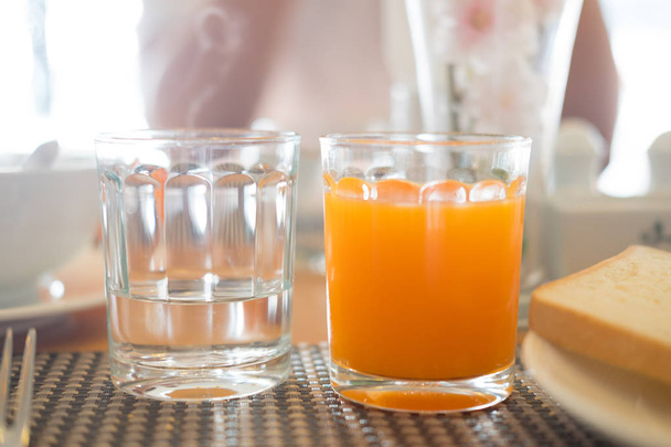 стакан воды и апельсиновый сок на столе для завтрака
 - Фото, изображение