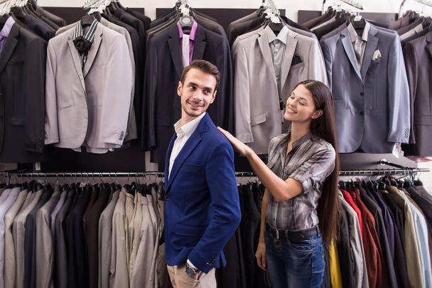 Girl seller helps to pick up a client in a jacket menswear bouti - 写真・画像