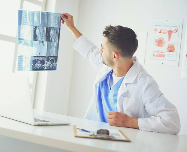 Fiatal orvos ül az irodájában, és elemzi a röntgen - Fotó, kép