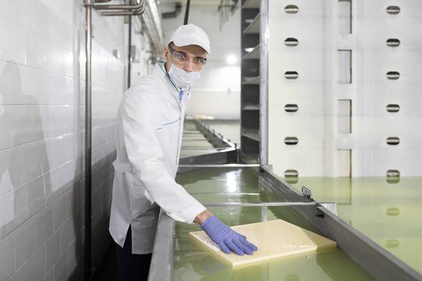 technologist put his hand on a piece of butter at the dairy plant - Photo, Image