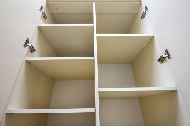 Interior de armario de plástico blanco o armario de ropa con muchos estantes vacíos con puertas abiertas. Diseño e instalación de mobiliario
. - Foto, imagen
