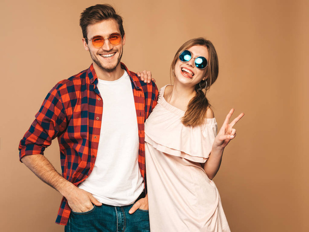 Portrait of Smiling Beautiful Girl and her Handsome Boyfriend laughing.Happy Cheerful Family. in sunglasses.Valentine's Day. Posing on beige wall. Hugging - Photo, image