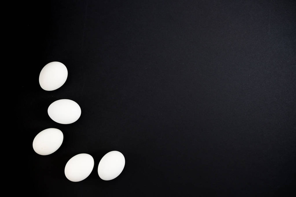 White eggs on a black background. Frame from the creative layout of white eggs on a black background - Zdjęcie, obraz