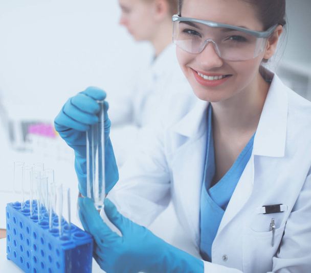Žena vědec je obklopen lékařskými lahvičkami a baňky, izolované na bílém pozadí - Fotografie, Obrázek