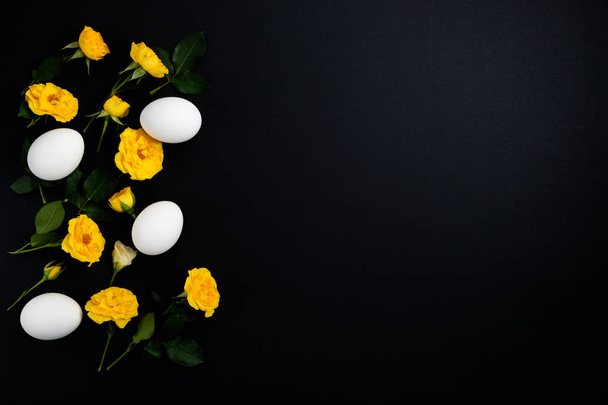 Frame made of flowers and eggs on a black background - Zdjęcie, obraz