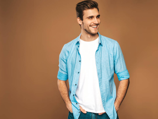 Porträt eines gutaussehenden lächelnden, stylischen Hipster-Geschäftsmann-Models in blauer Hemdkleidung. Modemann posiert auf goldenem Hintergrund - Foto, Bild