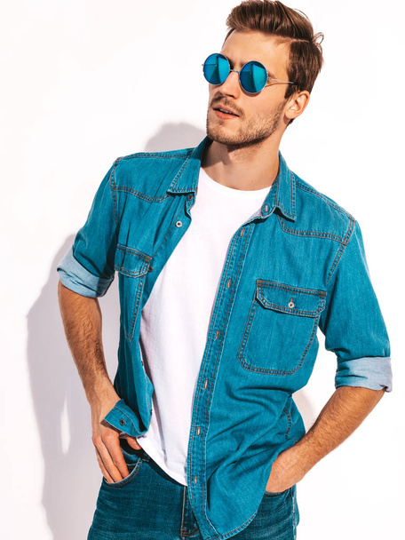 Portrait of handsome smiling stylish hipster lumbersexual businessman model dressed in jeans clothes. Fashion man wearing sunglasses. Isolated on white - Фото, изображение
