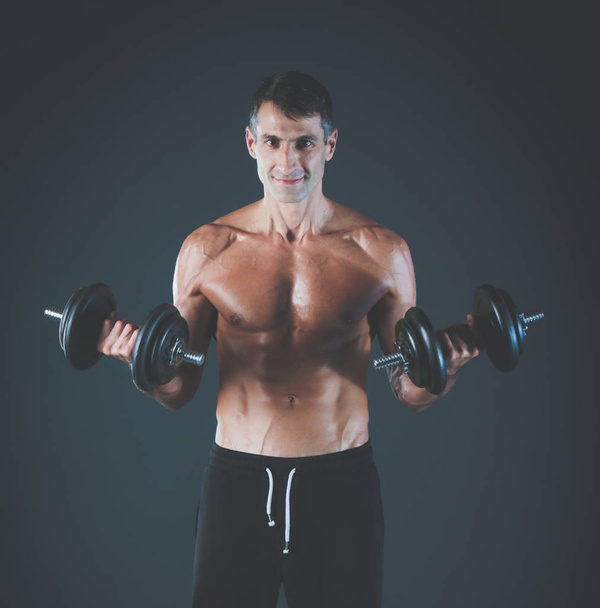 Handsome muscular man working out with dumbbells. Personal fitness instructor. Personal training. - Fotó, kép