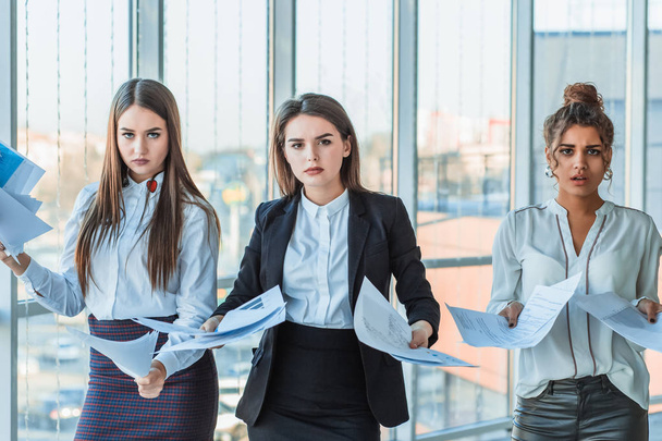 Three young beautiful brunette business ladies in the office. All serious, talking with each other - Foto, Bild