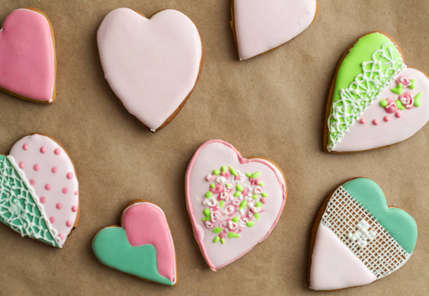 Gingerbread gingerbread in pink glaze, on craft background. Bakery products. Gingerbread in the shape of a heart. Place for text. Gingerbread pattern Background. - 写真・画像