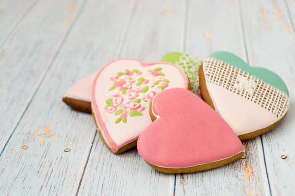 Painted gingerbread on a light wooden background. Tasty cookies in a forepe of hearts. Bakery products. There is for text. Love concept - 写真・画像