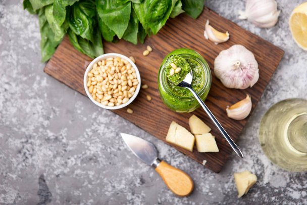 Pesto sauce in a bottle with ingredients (fresh basil, cheese, pine nuts, garlic) - Foto, immagini