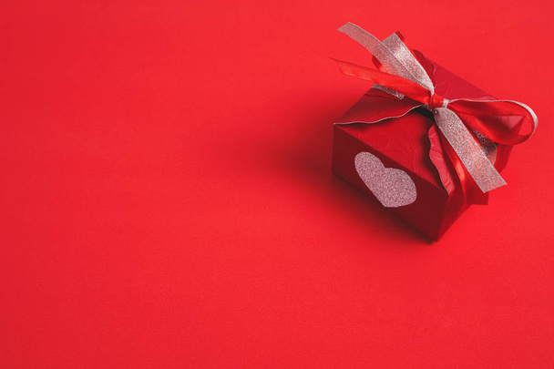 Gift box with a red bow on red background - Image - Zdjęcie, obraz