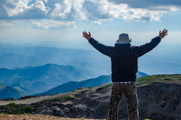 Wandelaar met verspreiding armen in een vreugdevolle pose, boven op een berg een landschap kijken - Foto, afbeelding